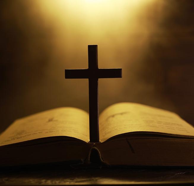 Cross on an open Bible with warm light in the background.